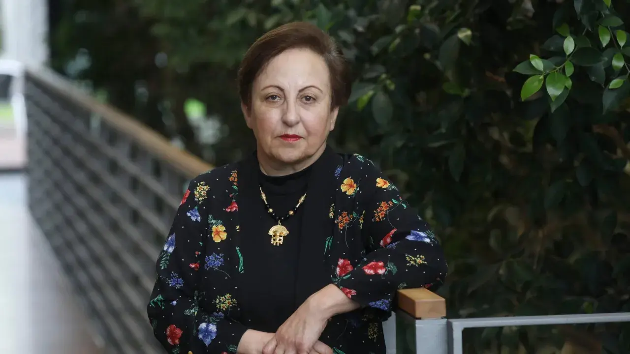 Shirin Ebadi, eine Frau mit starkem Blick, trägt eine schwarze Jacke mit bunten Blumen.