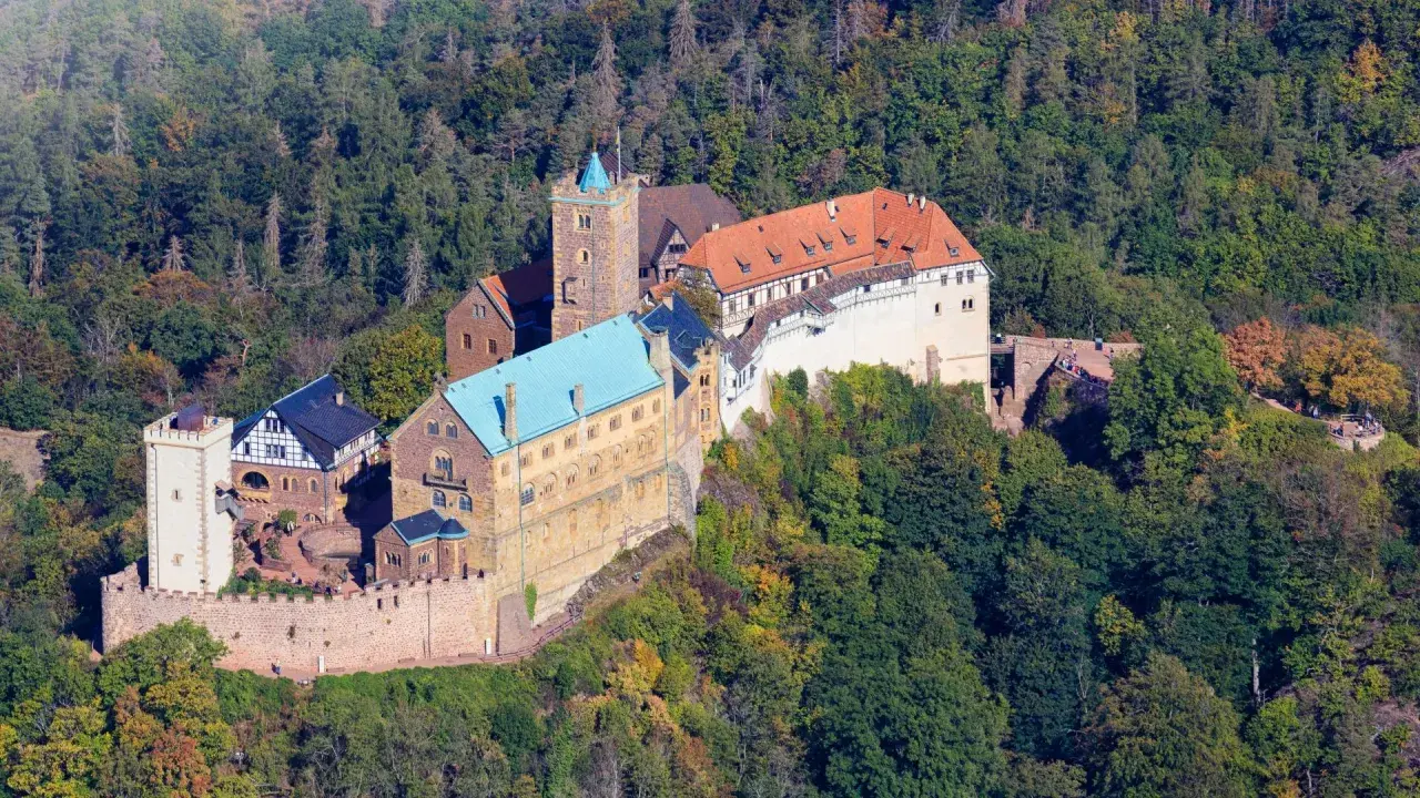 Die Wartburg, Ort von Luthers Thesen, thront auf einem bewaldeten Berg.