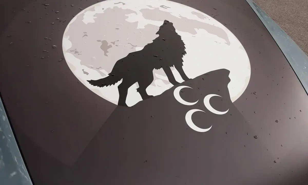 Ein grauer Wolf heult den Mond an, der auf einem Felsen steht. Drei weiße Halbmonde sind unter ihm.