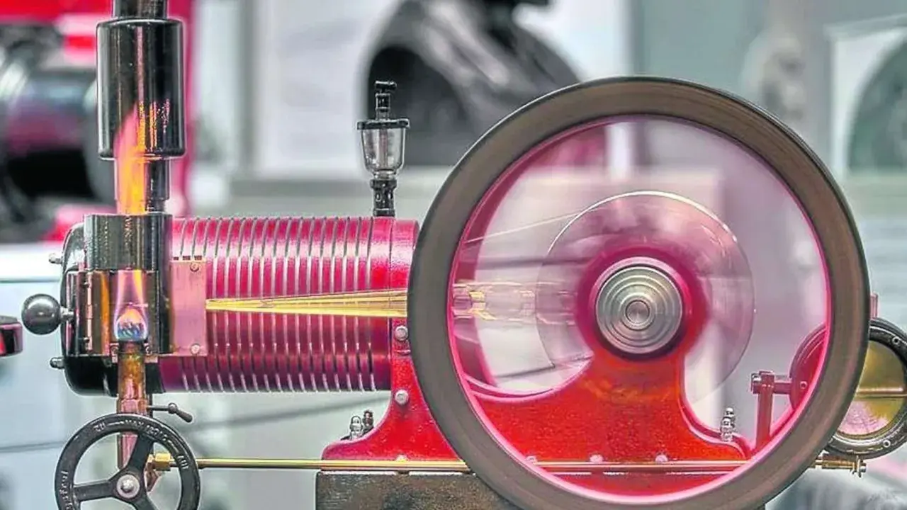 Eine funktionierende Denis Papin Dampfmaschine mit rot glühendem Kessel und einem sich drehenden Schwungrad.