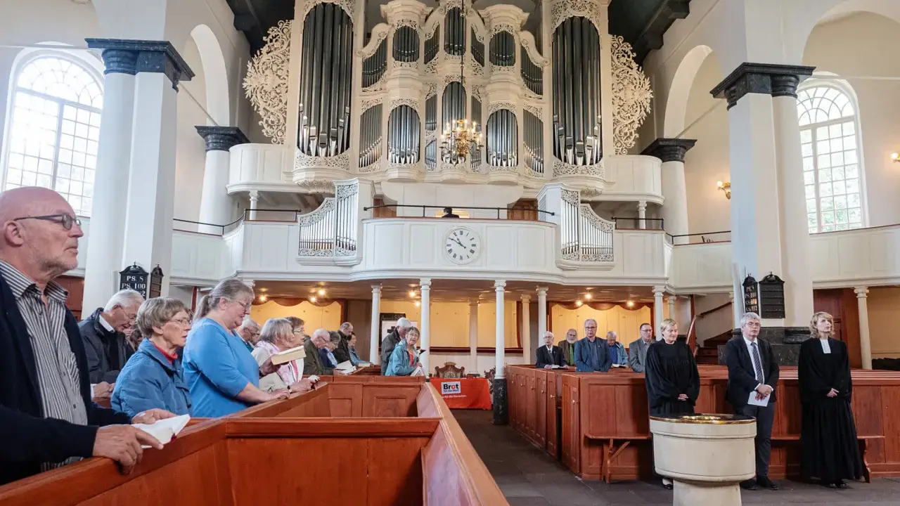 Gemeinde in einer reformierten Kirche mit imposanter Orgel.