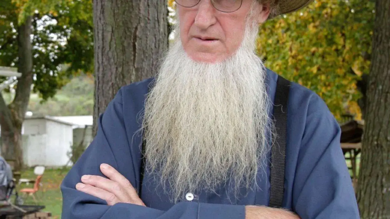 Ein älterer Amish-Mann mit langem, weißem Bart und Strohhut blickt nachdenklich.