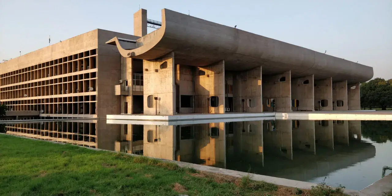 Le Corbusiers Kapitol-Gebäude in Chandigarh, Indien, spiegelt sich in einem ruhigen Wasserbecken.