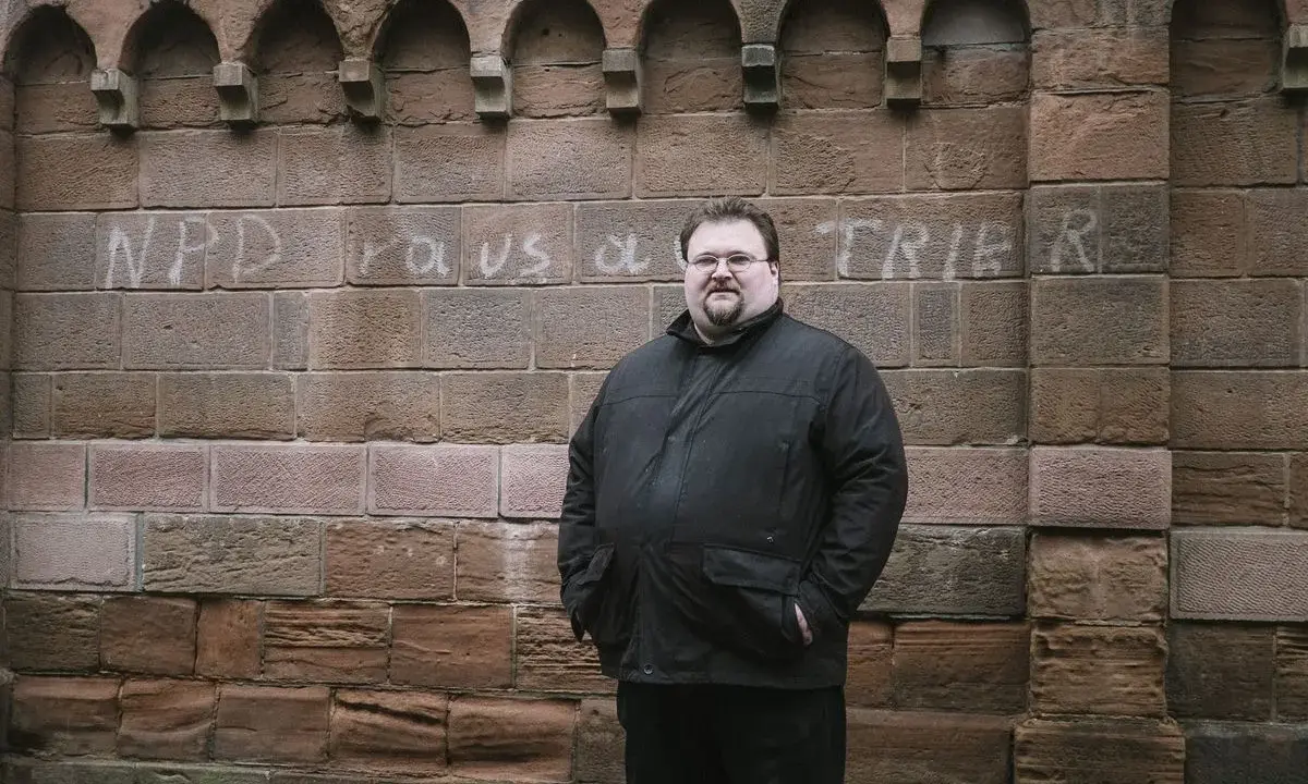 Safet Babic steht vor einer Mauer mit Graffiti.