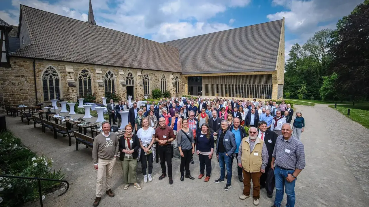 Eine Gruppe von Menschen versammelt sich vor einer historischen Kirche, die an die Kirche von England erinnert.