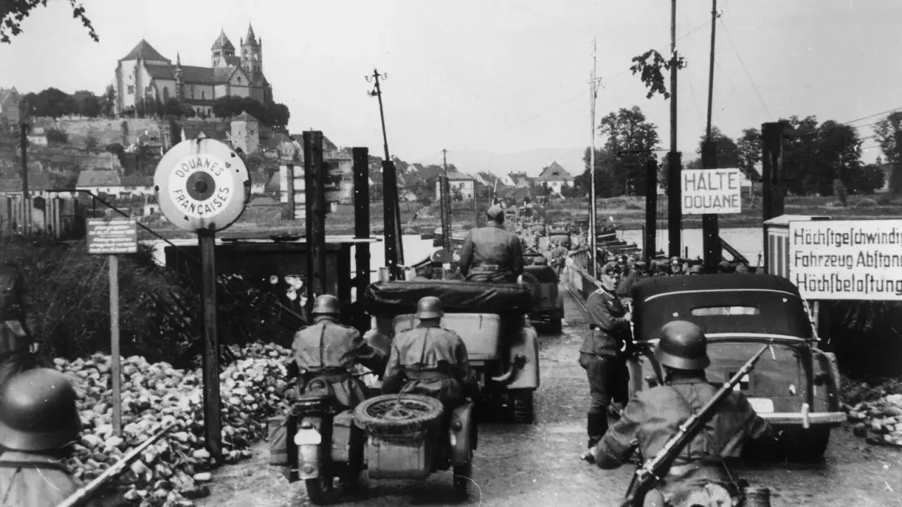 Soldaten kontrollieren Fahrzeuge an einer Grenze. Ein Schild zeigt "Douanes Françaises". Ein Blick auf die elsass geschichte.