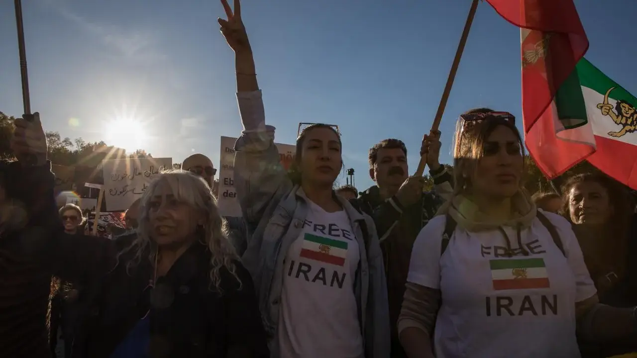 Menschen demonstrieren für ein free Iran. Eine Frau hält ein Schild mit der Aufschrift "Free Iran" und der iranischen Flagge.