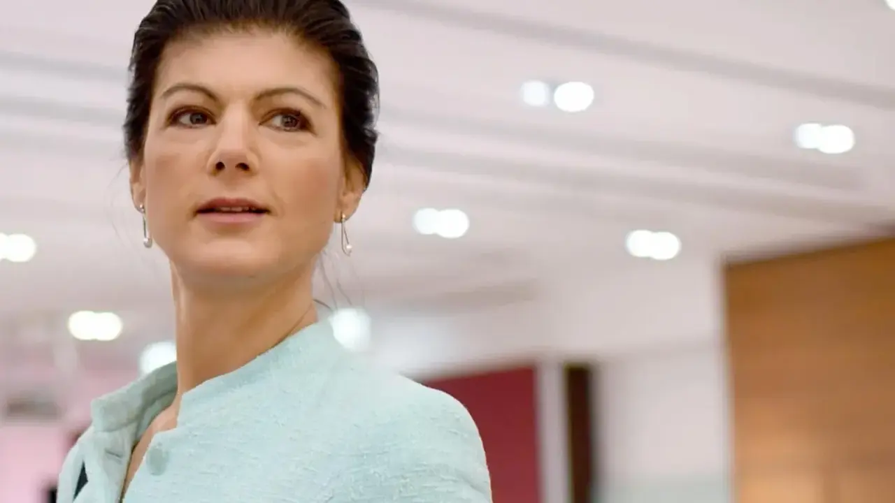 Sahra Wagenknecht, deren Herkunft oft diskutiert wird, blickt nachdenklich in die Ferne. Sie trägt ein hellblaues Jackett.