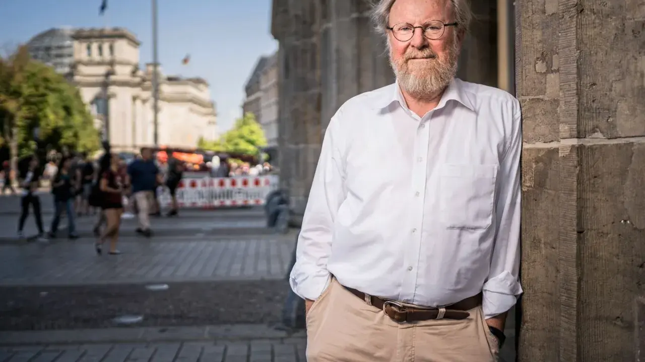Wolfgang Thierse, lächelnd, lehnt an einer Säule vor dem Reichstagsgebäude in Berlin.