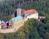 Die Wartburg, Ort von Luthers Thesen, thront auf einem bewaldeten Berg.