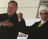 Erdogan und seine Frau, die ein Kopftuch trägt, halten Händchen.
