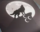 Ein grauer Wolf heult den Mond an, der auf einem Felsen steht. Drei weiße Halbmonde sind unter ihm.