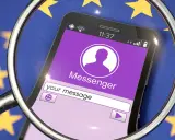 Lupe über Smartphone mit Messenger-App vor EU-Flagge. Diskussionen über Chatkontrolle EU.