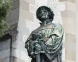 Bronzestatue von Huldrych Zwingli mit Buch und Schwert, ein Symbol für seinen Glauben und Kampf.