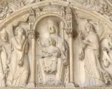 Steinrelief mit Maria und Kind, flankiert von Heiligen und Engeln. Die Bedeutung von Saint Germain wird hier durch die Darstellung von Heiligen und biblischen Szenen unterstrichen.
