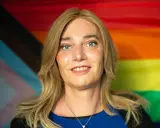 Markus Ganserer lächelt vor einer Pride-Flagge.