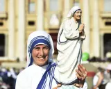 Eine Frau im Habit von Mutter Teresa hält eine Statue von ihr. Sie zeigt, was Mutter Teresa gemacht hat: Nächstenliebe und Hilfe für Bedürftige.