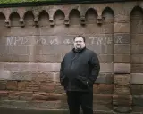 Safet Babic steht vor einer Mauer mit Graffiti.