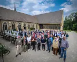Eine Gruppe von Menschen versammelt sich vor einer historischen Kirche, die an die Kirche von England erinnert.