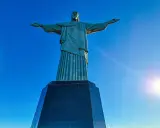 Cristo Redentor, die berühmte Statue in Rio de Janeiro, breitet seine Arme unter strahlend blauem Himmel aus.