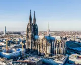 Majestätische gotische Kirchen ragen über einer Stadt auf. Der Kölner Dom, ein Meisterwerk gotischer Architektur, dominiert die Skyline.