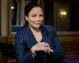 Karen Duve macht eine nachdenkliche Miene, während sie in einem gestreiften Blazer sitzt.