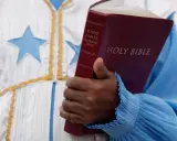 Eine Hand hält eine King James Bibel. Der **neues testament inhalt** wird hier durch das Buch repräsentiert, das in einer festlichen Robe mit Sternen getragen wird.