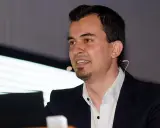Mann mit Mikrofon und Anzug spricht.