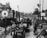 Soldaten kontrollieren Fahrzeuge an einer Grenze. Ein Schild zeigt "Douanes Françaises". Ein Blick auf die elsass geschichte.
