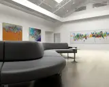 Moderne Galerie mit abstrakter Kunst und einem geschwungenen Sofa. Hier wird Kunstfreiheit gelebt, die Vielfalt der Ausdrucksformen ist beeindruckend.
