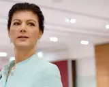Sahra Wagenknecht, deren Herkunft oft diskutiert wird, blickt nachdenklich in die Ferne. Sie trägt ein hellblaues Jackett.