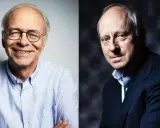 Zwei Männer, einer lächelnd mit Brille, der andere im Anzug, erinnern an die Gedanken von Michael Sandel zur Gerechtigkeit.
