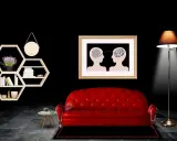 Ein rotes Sofa vor einem Bild, das zwei Köpfe mit verschlungenen Linien zeigt, symbolisiert die Seele. Ein Regal mit Büchern und eine Lampe vervollständigen die Szene.