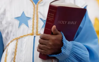 Eine Hand hält eine King James Bibel. Der **neues testament inhalt** wird hier durch das Buch repräsentiert, das in einer festlichen Robe mit Sternen getragen wird.