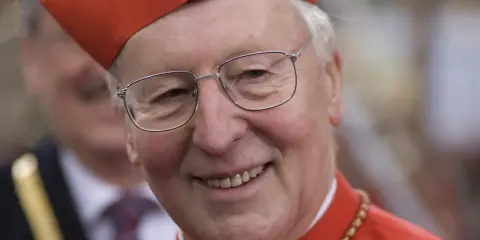 Ein lächelnder Kardinal Wetter trägt seine rote Kopfbedeckung und Brille.