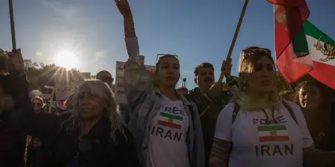 Menschen demonstrieren für ein free Iran. Eine Frau hält ein Schild mit der Aufschrift "Free Iran" und der iranischen Flagge.