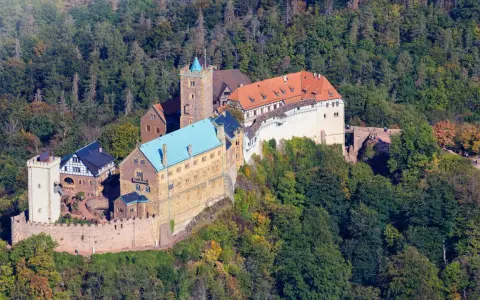 Die Wartburg, Ort von Luthers Thesen, thront auf einem bewaldeten Berg.