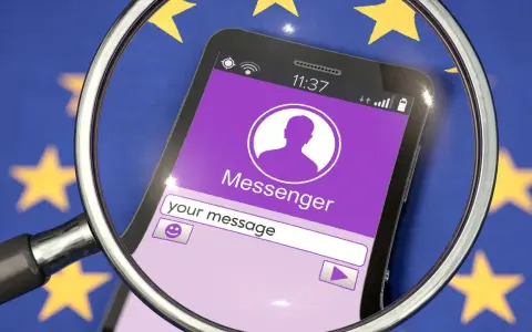 Lupe über Smartphone mit Messenger-App vor EU-Flagge. Diskussionen über Chatkontrolle EU.