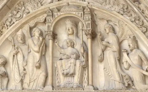 Steinrelief mit Maria und Kind, flankiert von Heiligen und Engeln. Die Bedeutung von Saint Germain wird hier durch die Darstellung von Heiligen und biblischen Szenen unterstrichen.