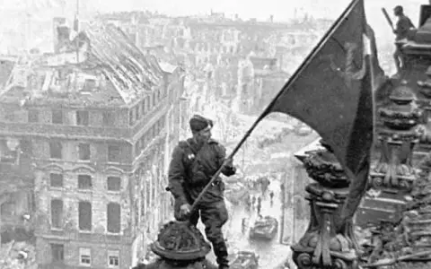 Ein Soldat hisst am 8. Mai die Flagge über den Ruinen Berlins.