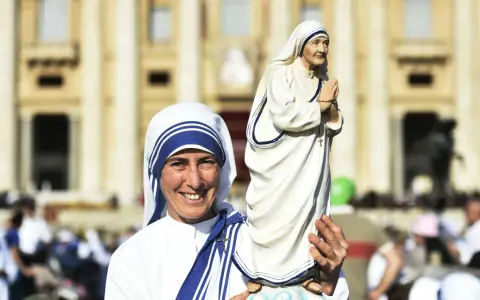 Eine Frau im Habit von Mutter Teresa hält eine Statue von ihr. Sie zeigt, was Mutter Teresa gemacht hat: Nächstenliebe und Hilfe für Bedürftige.