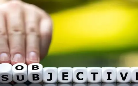 Finger tippt auf Würfel mit "SUBJEKTIV". Der Unterschied zwischen objektiv und subjektiv wird hier bildlich dargestellt.