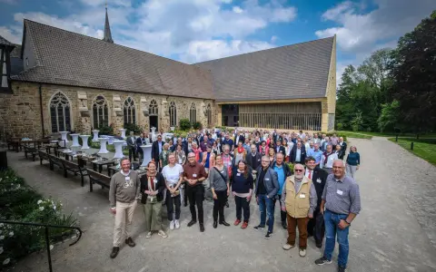 Eine Gruppe von Menschen versammelt sich vor einer historischen Kirche, die an die Kirche von England erinnert.