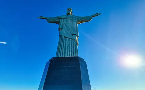 Cristo Redentor, die berühmte Statue in Rio de Janeiro, breitet seine Arme unter strahlend blauem Himmel aus.