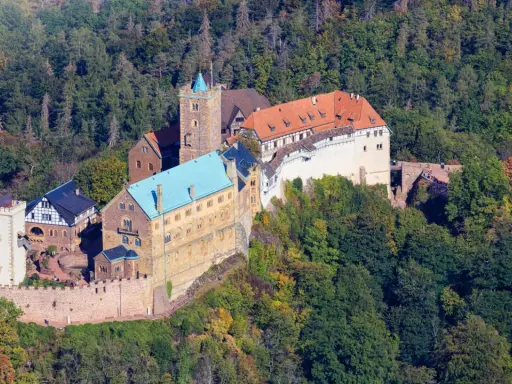 Die Wartburg, Ort von Luthers Thesen, thront auf einem bewaldeten Berg.