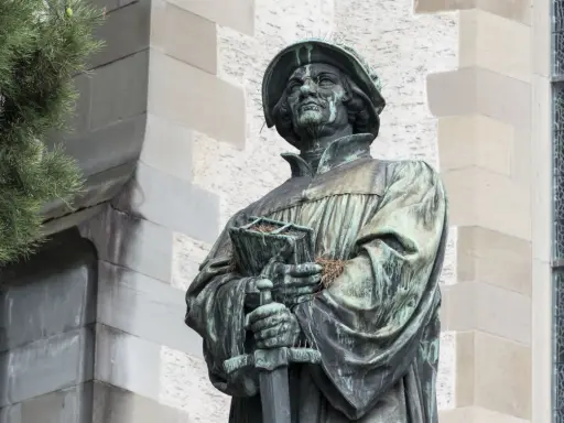 Bronzestatue von Huldrych Zwingli mit Buch und Schwert, ein Symbol für seinen Glauben und Kampf.