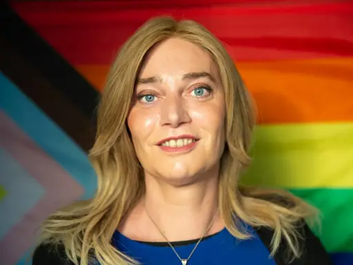 Markus Ganserer lächelt vor einer Pride-Flagge.