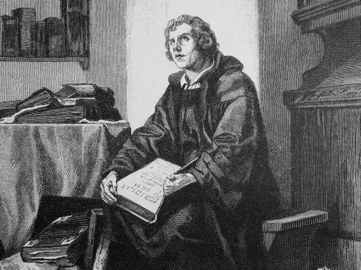 Martin Luther sitzt in seinem Studierzimmer und schreibt an seiner Bibelübersetzung. Bücher stapeln sich um ihn herum.