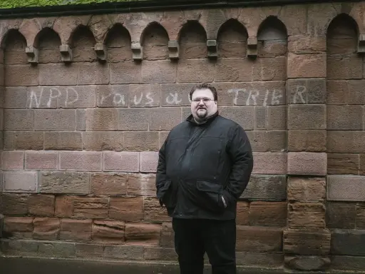 Safet Babic steht vor einer Mauer mit Graffiti.