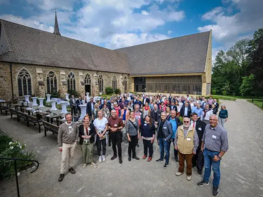 Eine Gruppe von Menschen versammelt sich vor einer historischen Kirche, die an die Kirche von England erinnert.